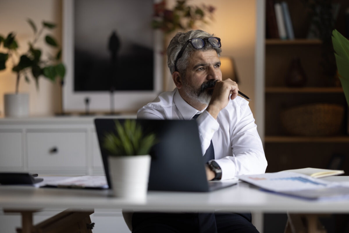 Mature adult businessman concentrating at home office. He is thinking, focused on remote work, making a decision