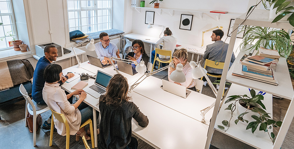 open office space with people working and collaborating at a table in one room