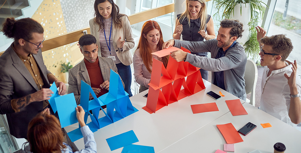 two teams of professionals building towers out of paper