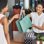 female retail employee handing a bag to a female customer