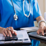 health care worker working on a calculator and computer