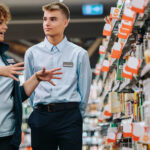 two retail employees talking in store aisle.