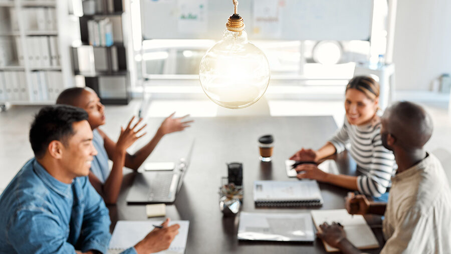 group of business people sitting around a table with a light bulb above them
