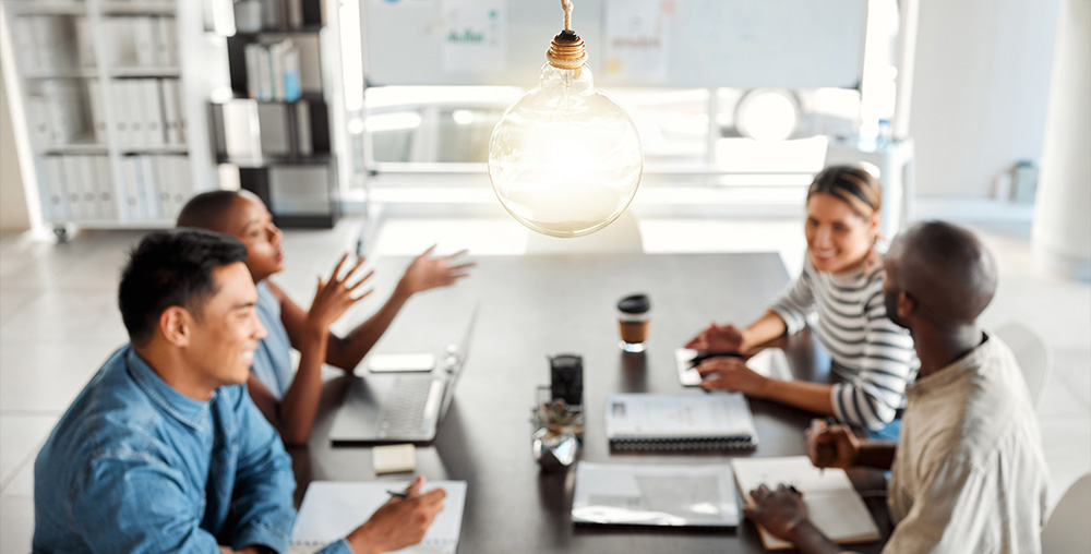 group of business people sitting around a table with a light bulb above them