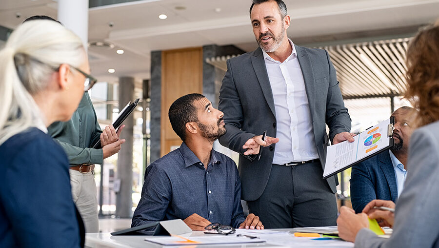 adult male manager leading discussion at a table of professionals