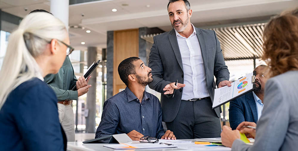 adult male manager leading discussion at a table of professionals