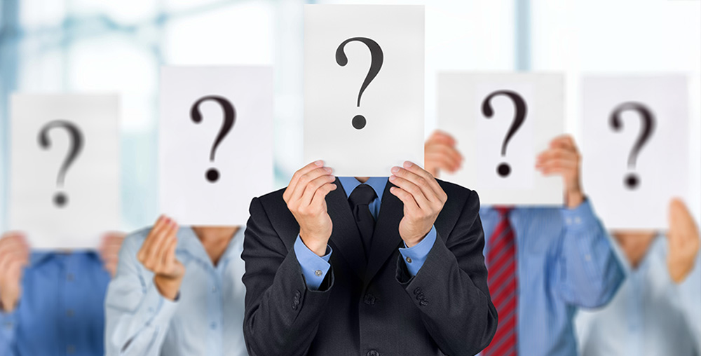 people holding papers of question marks in front of their faces.