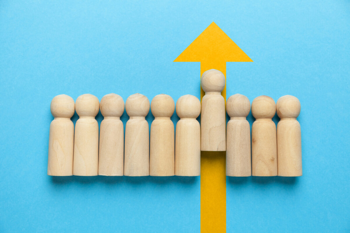 wooden figure blocks with one rising on a yellow up arrow