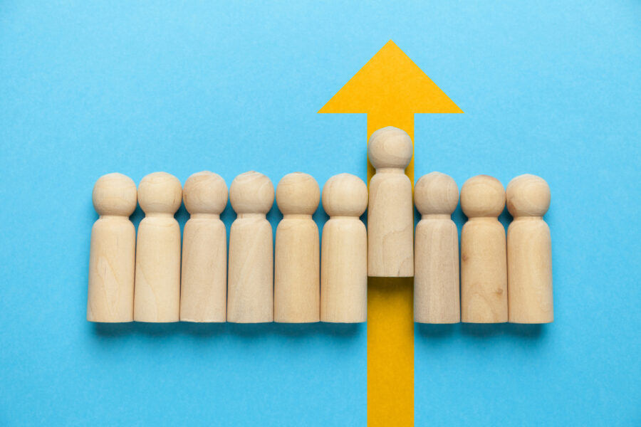 wooden figure blocks with one rising on a yellow up arrow