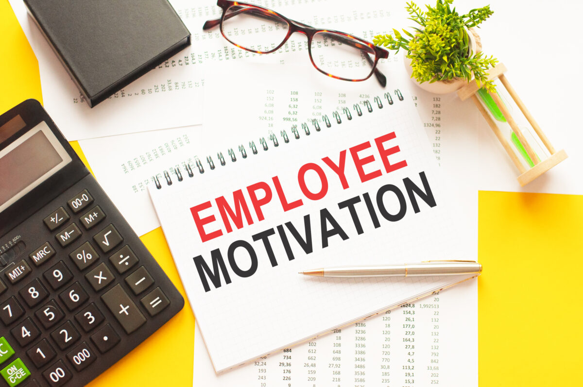 employee motivation written notebook with calculate and glasses by it