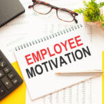 employee motivation written notebook with calculate and glasses by it