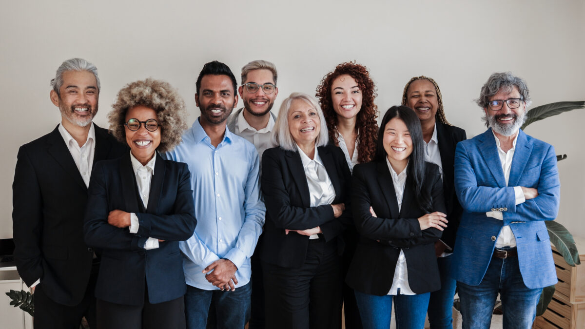 Multi generational business professionals standing and smiling.